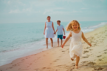 happy family on beach, cute little girl with mom and brother at sea