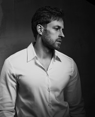 Serious sad business man thinking in white style shirt and on dark shadow background. Closeup....