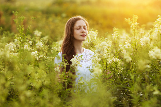 Happy beautiful girl stands among wildflowers