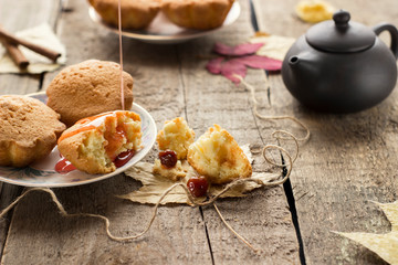Muffins with jam on wooden background. Pouring jam on a cupcake.