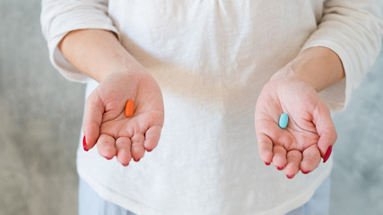 Personal dilemma. Choice concept. Woman holding red and blue capsule choosing between.