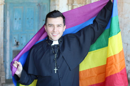 Priest holding the rainbow flag 