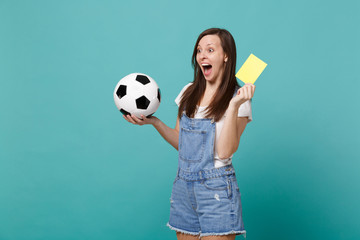 Excited screaming woman football fan support team with soccer ball, yellow card, propose player retire from field isolated on blue turquoise background. People emotions, sport family leisure concept.