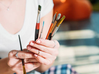 Artwork tools. Studio workplace. Paintbrushes assortment in artist hands closeup.