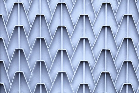 Patterned metal fence with outdated bright gray paint. Abstract texture background.