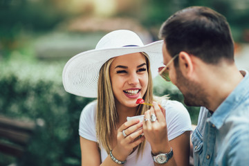 Couple joking and having fun while eating an ice cream in the park.