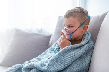 Boy making inhalation with nebulizer at home. Child asthma inhaler inhalation nebulizer steam sick...