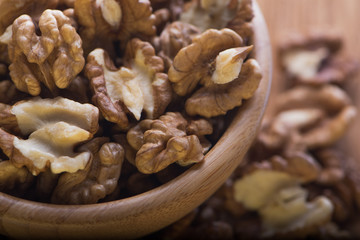 Top close up view of group of large dried ukranian russian peeled Walnut kernels in a bowl on rustic wooden background