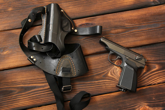 Weapon. The gun and holster for a handgun on wooden background
