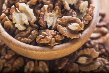 Top close up view of group of large dried ukranian russian peeled Walnut kernels in a bowl on rustic wooden background