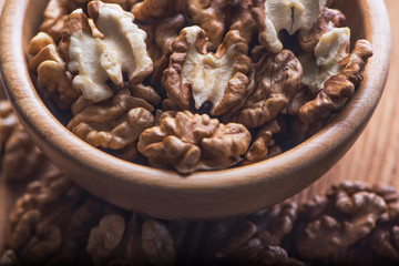 Top close up view of group of large dried ukranian russian peeled Walnut kernels in a bowl on rustic wooden background