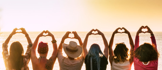 Group of diversity alternative young woman enjoying the sunset at the sea doing hearth symbol with hands - people enjoying friendly lifestyle - vacation in friendship concept for females - obrazy, fototapety, plakaty