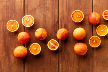 Organic blood oranges, whole and cut, shot from the top on a dark rustic wooden background with a...