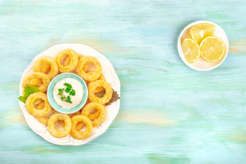 Squid rings with mayo and lemon on a teal blue background with a place for text