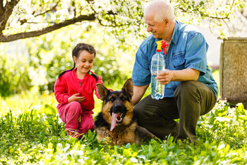 Grandfather with granddaughter dog and a dog in the garden