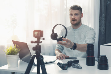 technology blogger recording headphone review in front of camera at home