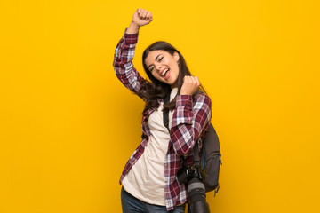 Photographer teenager girl over yellow wall celebrating a victory
