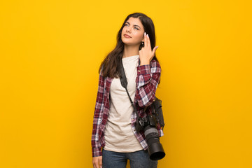 Photographer teenager girl over yellow wall with problems making suicide gesture