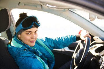girl driving a car while preparing for skiing on a snowy mountain