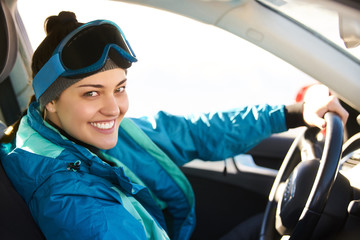 girl driving a car while preparing for skiing on a snowy mountain