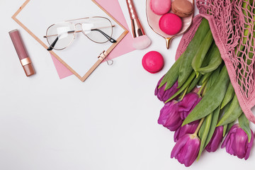Purple tulips, macarons and sylish feminine accessories on the white table