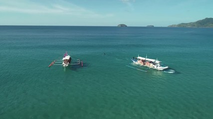Aerial shot of a two filipino touristic boats floating in turquoise pristine water. Palawan Island, Philippines