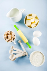 Baking ingredients and tools on trendy bright blue background - flour, eggs, sugar, milk, butter, layout, flatlay top view copy space banner