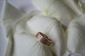 Wedding ring on white petals of roses.