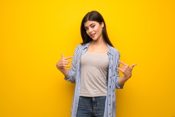 Teenager girl over yellow wall proud and self-satisfied