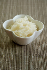 Sticky rice in white bowl on brown asian styled mat and space for write wording, Tradition food of Thai north eastern people, sold in market and restaurant