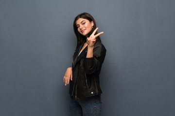 Teenager girl over grey wall smiling and showing victory sign