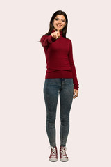 Fototapeta premium A full-length shot of a Teenager girl with turtleneck showing and lifting a finger over isolated background