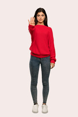 A full-length shot of a Teenager girl with red sweater making stop gesture denying a situation that thinks wrong over isolated background