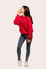 A full-length shot of a Teenager girl with red sweater shouting with mouth wide open to the lateral over isolated background