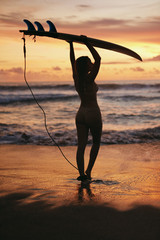 Summer. Surfer girl silhouette with surf board on sunset beach