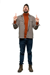 Full-length shot of Handsome man with beard surprised and pointing up on isolated white background