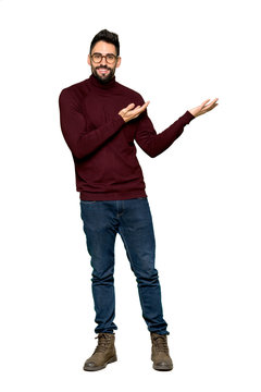 Full-length shot of Handsome man with glasses extending hands to the side for inviting to come on isolated white background