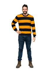 Naklejka premium Full-length shot of Handsome man with striped sweater posing with arms at hip and smiling on isolated white background