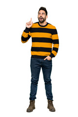 Full-length shot of Handsome man with striped sweater thinking an idea pointing the finger up on isolated white background