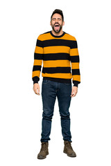 Fototapeta premium Full-length shot of Handsome man with striped sweater shouting to the front with mouth wide open on isolated white background