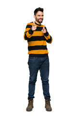 Full-length shot of Handsome man with striped sweater pointing to the front and smiling on isolated white background