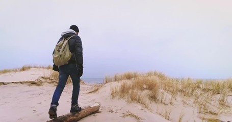 Man having a walk on a sandy beach by the sea. Cold weather. Wild coastline.