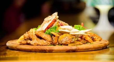 Enjoy your meal. Meat snack for group friends. Tasty delicious snacks. Snack for beer. Restaurant food. Wooden board french fries fish sticks burrito and meat steak served with salad. Pub menu snack