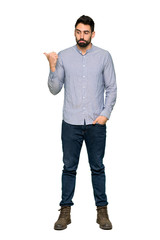 Full-length shot of Elegant man with shirt unhappy and pointing to the side on isolated white background
