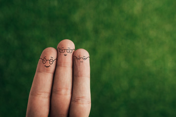 cropped view of happy fingers in eyeglasses on green