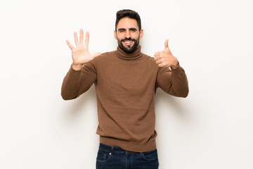 Fototapeta premium Handsome man over white wall counting six with fingers