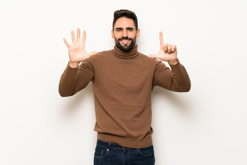 Handsome man over white wall counting seven with fingers