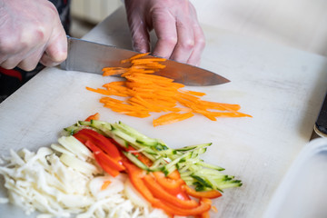 Chef cuts the vegetables into a meal. Preparing dishes. A man uses a knife and cooks.