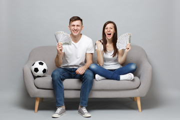 Laughing couple woman man football fans cheer up support favorite team holding fan of money in...