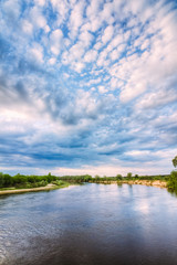 A river on a summer day with a cloudy sky above the horizon